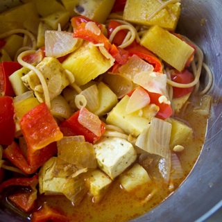 malaysian style laksa curry with tofu, red bell peppers, onions, potatoes, pineapple, and noodles